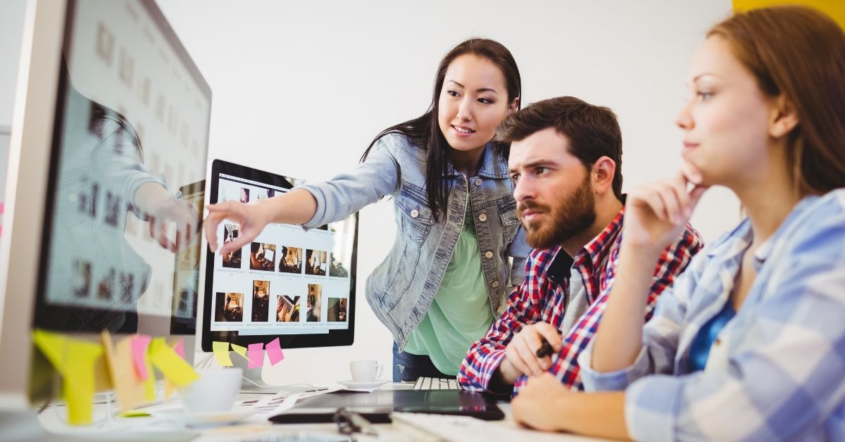 Funcionários de uma empresa analisam no computador quanto custa um site